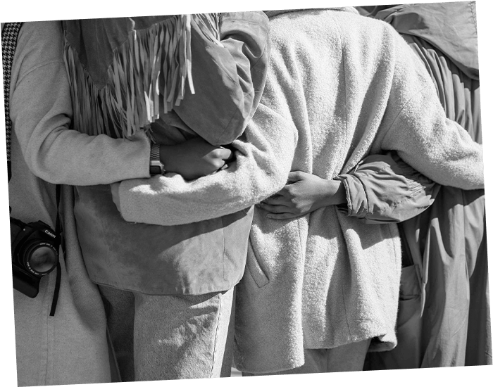 a view of four women from behind standing in an embrace